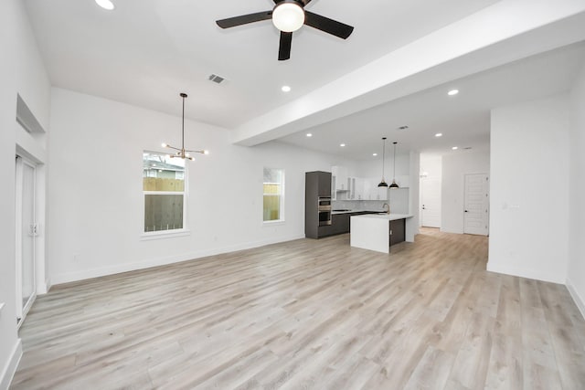 unfurnished living room with recessed lighting, visible vents, light wood-style flooring, and ceiling fan with notable chandelier