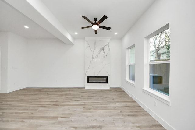 unfurnished living room with light wood-type flooring, a fireplace, baseboards, and recessed lighting