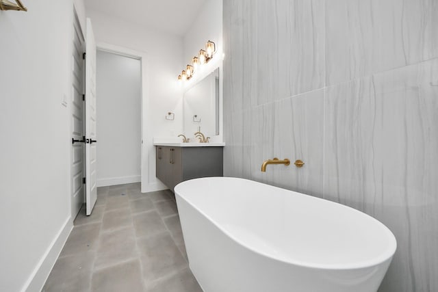 bathroom with concrete floors, baseboards, a freestanding bath, and vanity