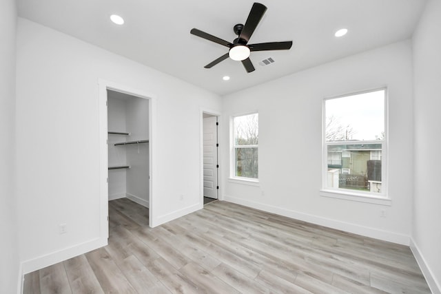 unfurnished bedroom with baseboards, a ceiling fan, a spacious closet, light wood-type flooring, and recessed lighting