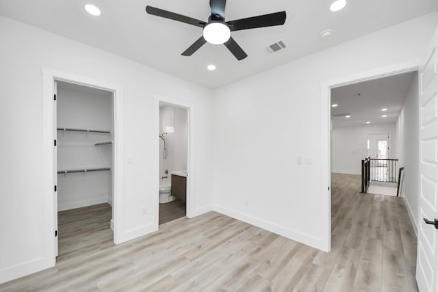 unfurnished bedroom featuring recessed lighting, a walk in closet, visible vents, and light wood-style floors