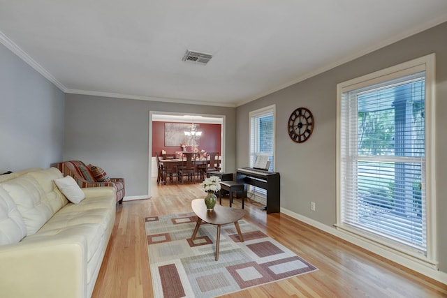 living room featuring crown molding, a chandelier, and light hardwood / wood-style flooring