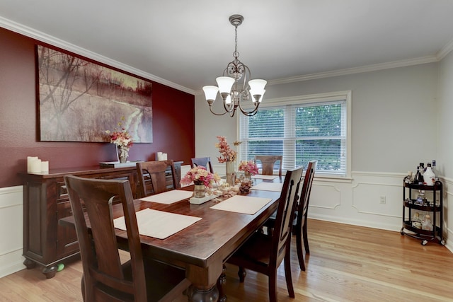 dining room with crown molding, light hardwood / wood-style floors, and a notable chandelier