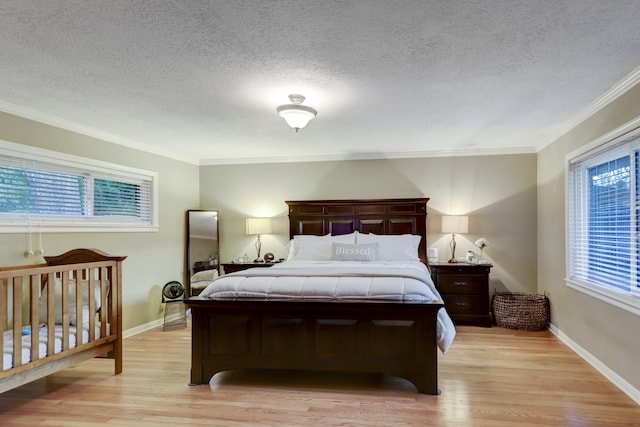 bedroom with ornamental molding, light hardwood / wood-style floors, and a textured ceiling