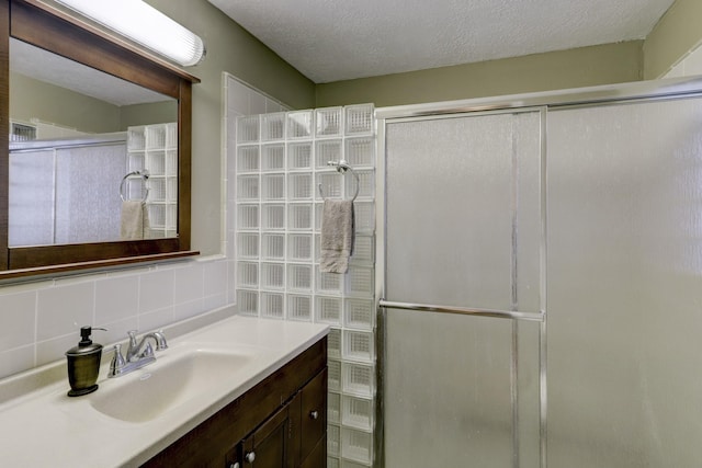 bathroom with vanity, backsplash, a textured ceiling, and walk in shower