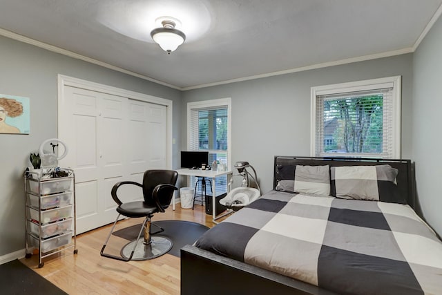 bedroom featuring multiple windows, crown molding, light hardwood / wood-style flooring, and a closet