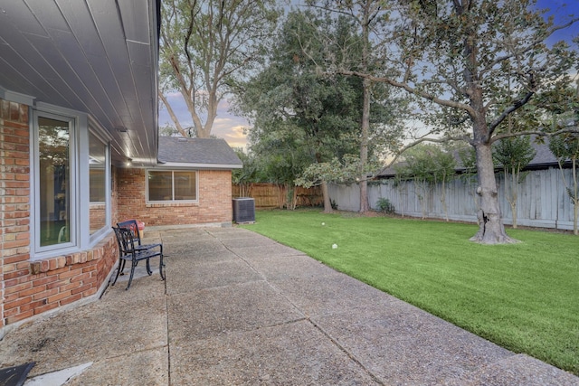 patio terrace at dusk with central AC and a lawn