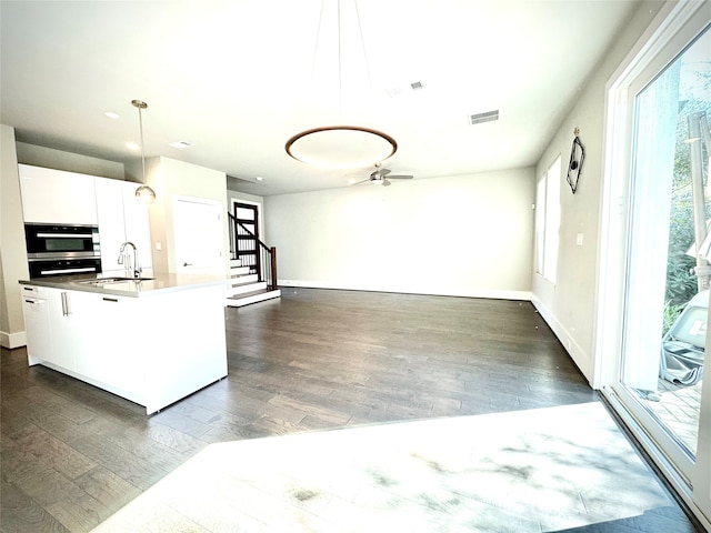 kitchen with sink, dark wood-type flooring, white cabinetry, decorative light fixtures, and stainless steel oven