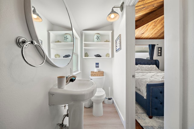 bathroom with vaulted ceiling, a healthy amount of sunlight, toilet, and hardwood / wood-style floors