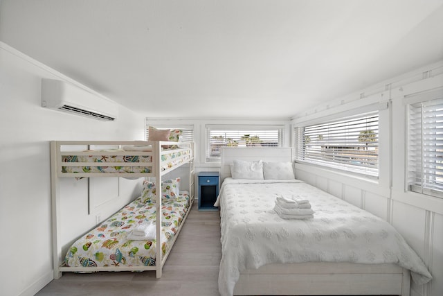 bedroom with wood-type flooring and an AC wall unit