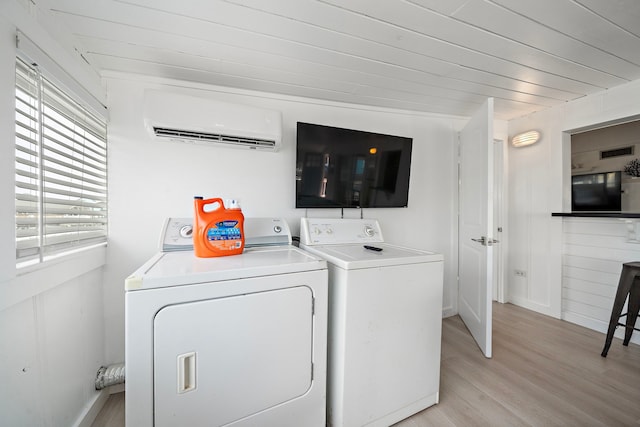 laundry room featuring light hardwood / wood-style flooring, a wall mounted air conditioner, plenty of natural light, and independent washer and dryer