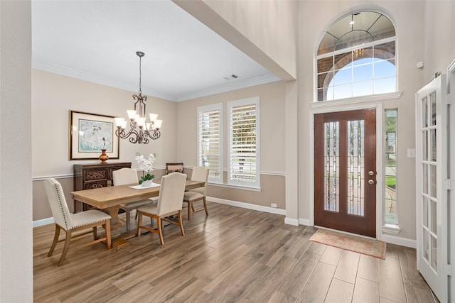 entrance foyer featuring visible vents, an inviting chandelier, ornamental molding, wood finished floors, and baseboards