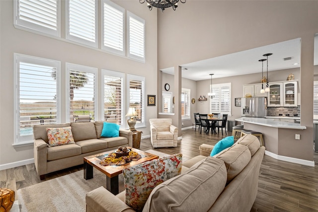 living area featuring dark wood-style floors, baseboards, visible vents, and a chandelier