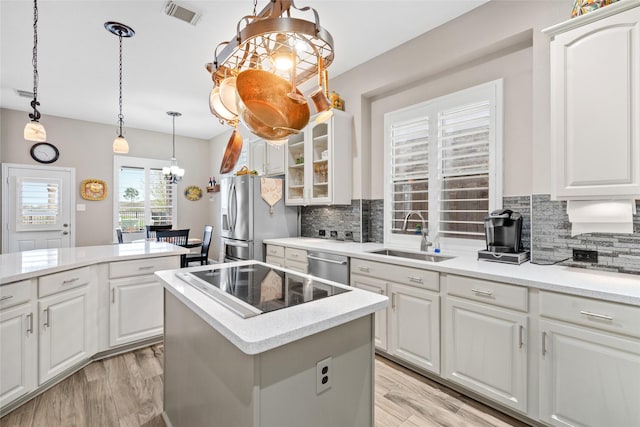 kitchen with stainless steel appliances, a sink, light countertops, and white cabinets