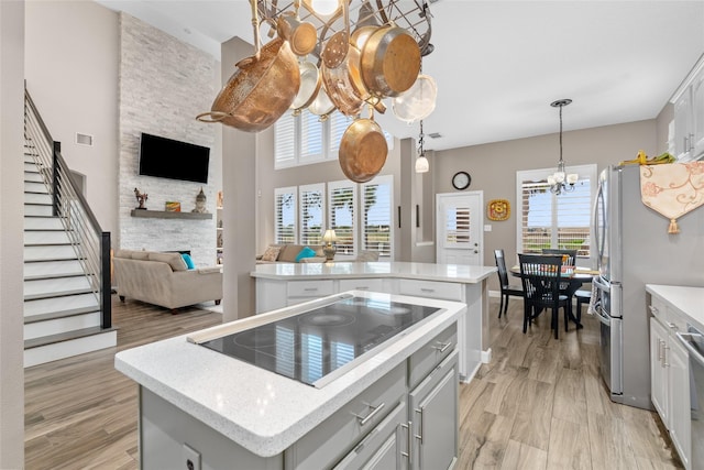 kitchen with a kitchen island, open floor plan, an inviting chandelier, black electric cooktop, and light countertops