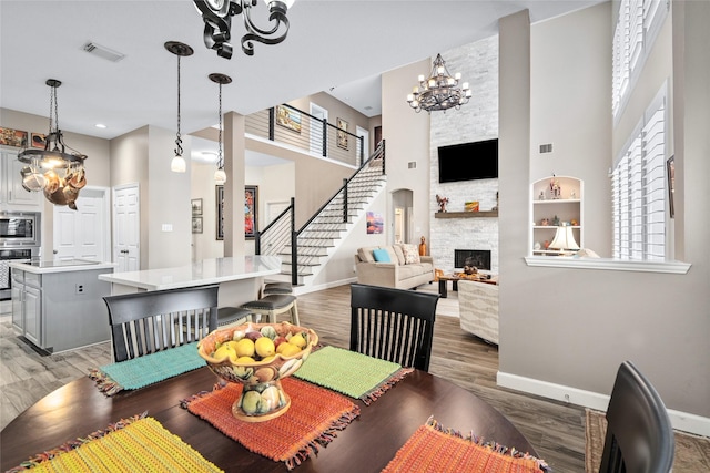 dining area with baseboards, visible vents, wood finished floors, stairs, and a fireplace