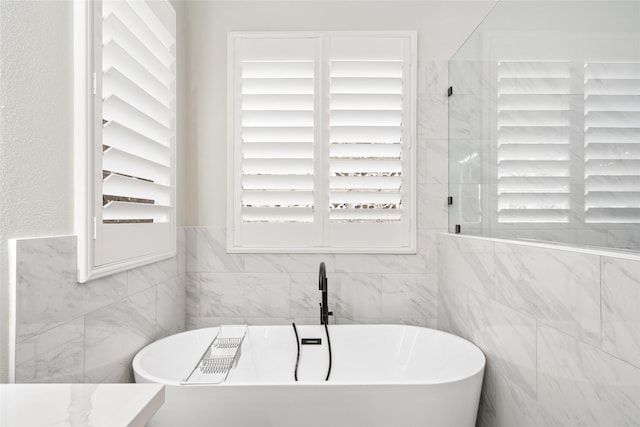 full bathroom with a freestanding tub and tile walls