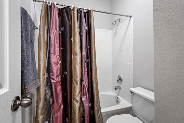 bathroom with a textured wall, shower / bath combination with curtain, and toilet