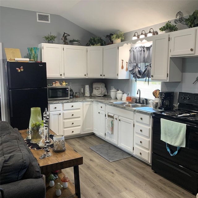 kitchen with vaulted ceiling, sink, white cabinets, and black appliances