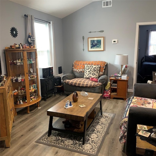 living room featuring lofted ceiling, plenty of natural light, and light hardwood / wood-style floors