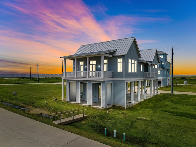 back house at dusk with a balcony and a lawn