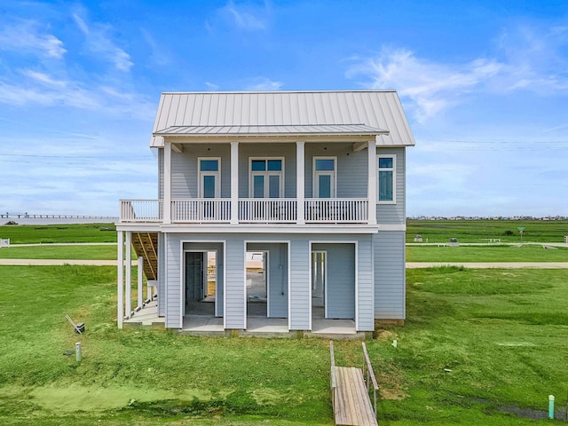 view of front of house with a patio, a balcony, a rural view, and a front lawn