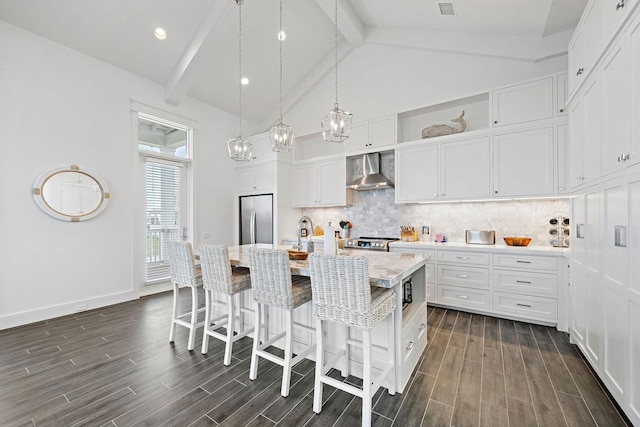 kitchen with appliances with stainless steel finishes, tasteful backsplash, white cabinetry, a center island with sink, and wall chimney exhaust hood