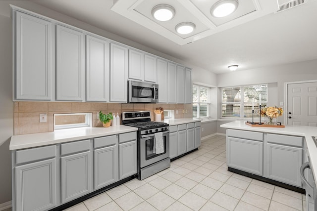 kitchen with tasteful backsplash, light tile patterned floors, gray cabinetry, and appliances with stainless steel finishes