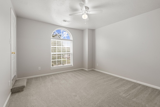 carpeted spare room with a textured ceiling and ceiling fan