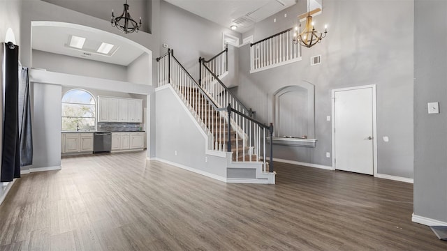 unfurnished living room featuring a high ceiling, dark hardwood / wood-style floors, sink, and a chandelier