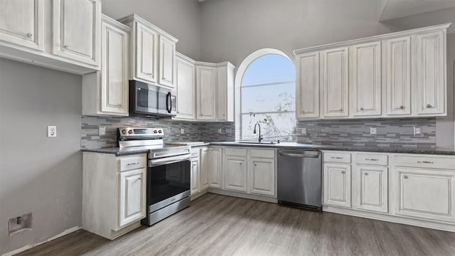 kitchen featuring sink, white cabinetry, light hardwood / wood-style flooring, stainless steel appliances, and decorative backsplash