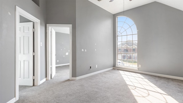 carpeted empty room with ceiling fan and high vaulted ceiling