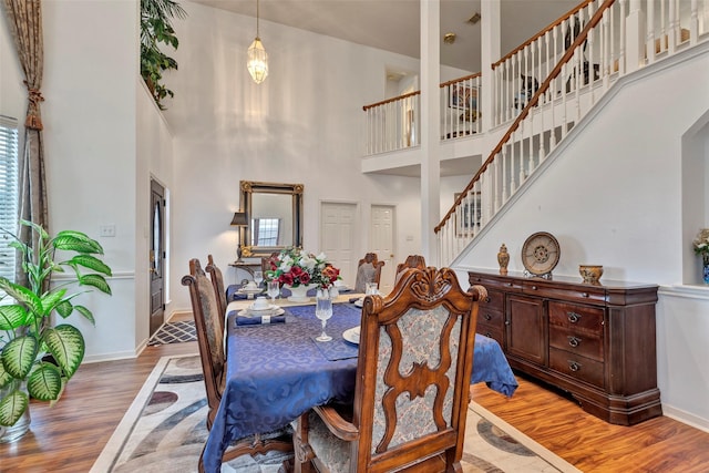 dining room featuring a towering ceiling and wood-type flooring