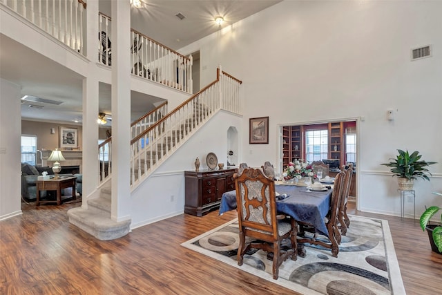 dining area with hardwood / wood-style floors, plenty of natural light, and a high ceiling