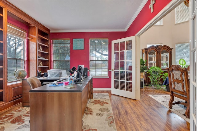 home office with built in shelves, ornamental molding, light hardwood / wood-style floors, and a healthy amount of sunlight