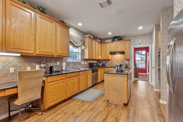 kitchen featuring sink, stainless steel appliances, tasteful backsplash, a kitchen island, and light wood-type flooring