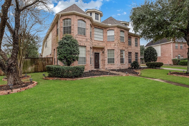 view of front facade featuring a front lawn, fence, and brick siding