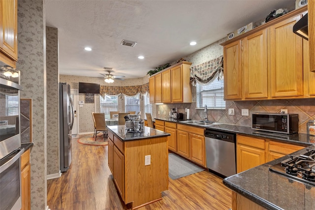 kitchen featuring sink, a kitchen island, ceiling fan, light hardwood / wood-style floors, and black appliances