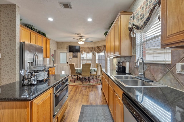 kitchen featuring sink, tasteful backsplash, appliances with stainless steel finishes, ceiling fan, and light hardwood / wood-style floors