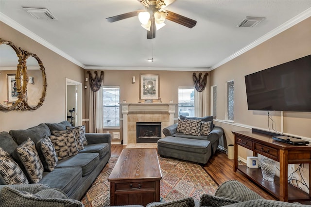 living room featuring hardwood / wood-style floors, crown molding, a fireplace, and ceiling fan