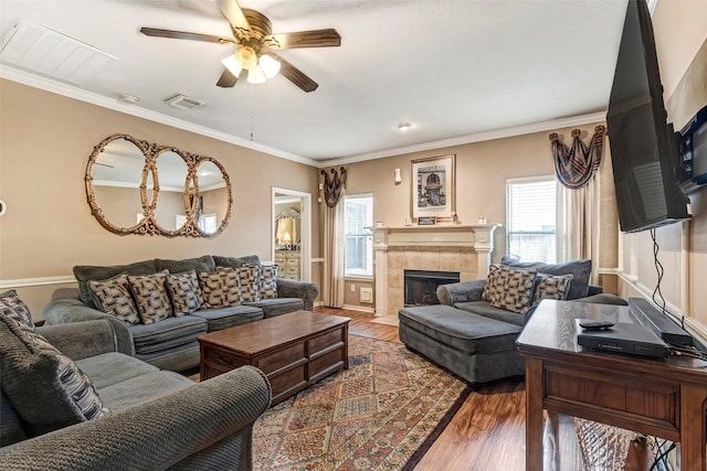 living room with a tiled fireplace, crown molding, dark hardwood / wood-style floors, and ceiling fan