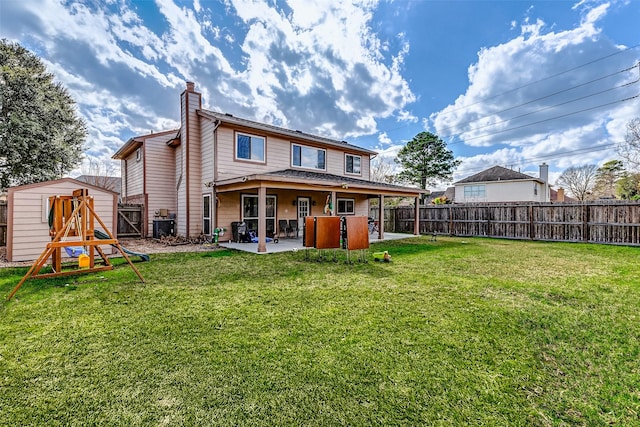 back of property featuring a yard, a patio, and a storage unit