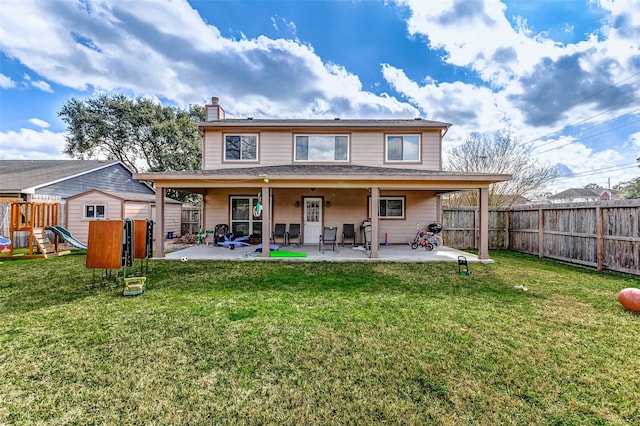 back of house featuring a patio area, a playground, and a lawn