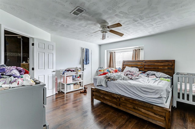 bedroom featuring dark wood-type flooring, ceiling fan, and a textured ceiling