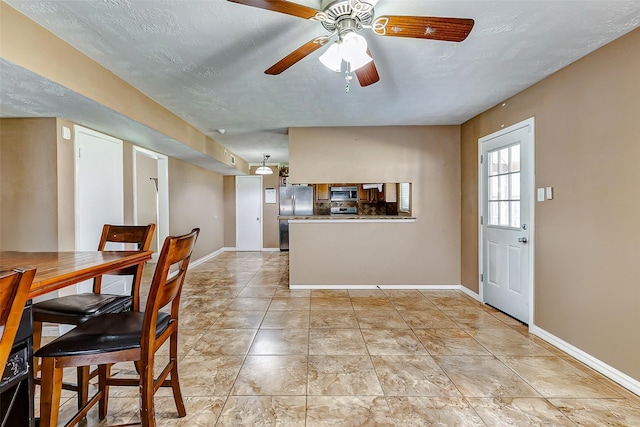 dining space with a textured ceiling, ceiling fan, and light tile patterned flooring