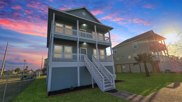 back house at dusk with a balcony and a yard