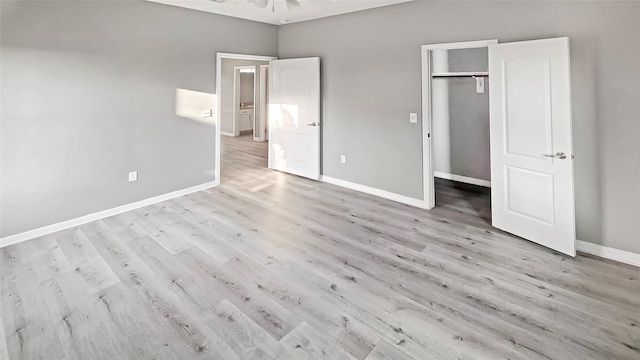 unfurnished bedroom featuring a closet, a spacious closet, and light hardwood / wood-style flooring