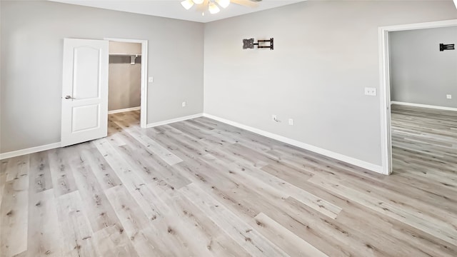 unfurnished bedroom featuring a walk in closet, light hardwood / wood-style floors, and a closet