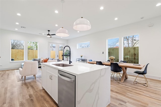 kitchen featuring sink, a center island with sink, hanging light fixtures, stainless steel dishwasher, and white cabinets