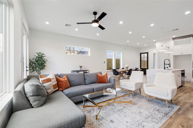 living room with sink, ceiling fan, and light hardwood / wood-style flooring